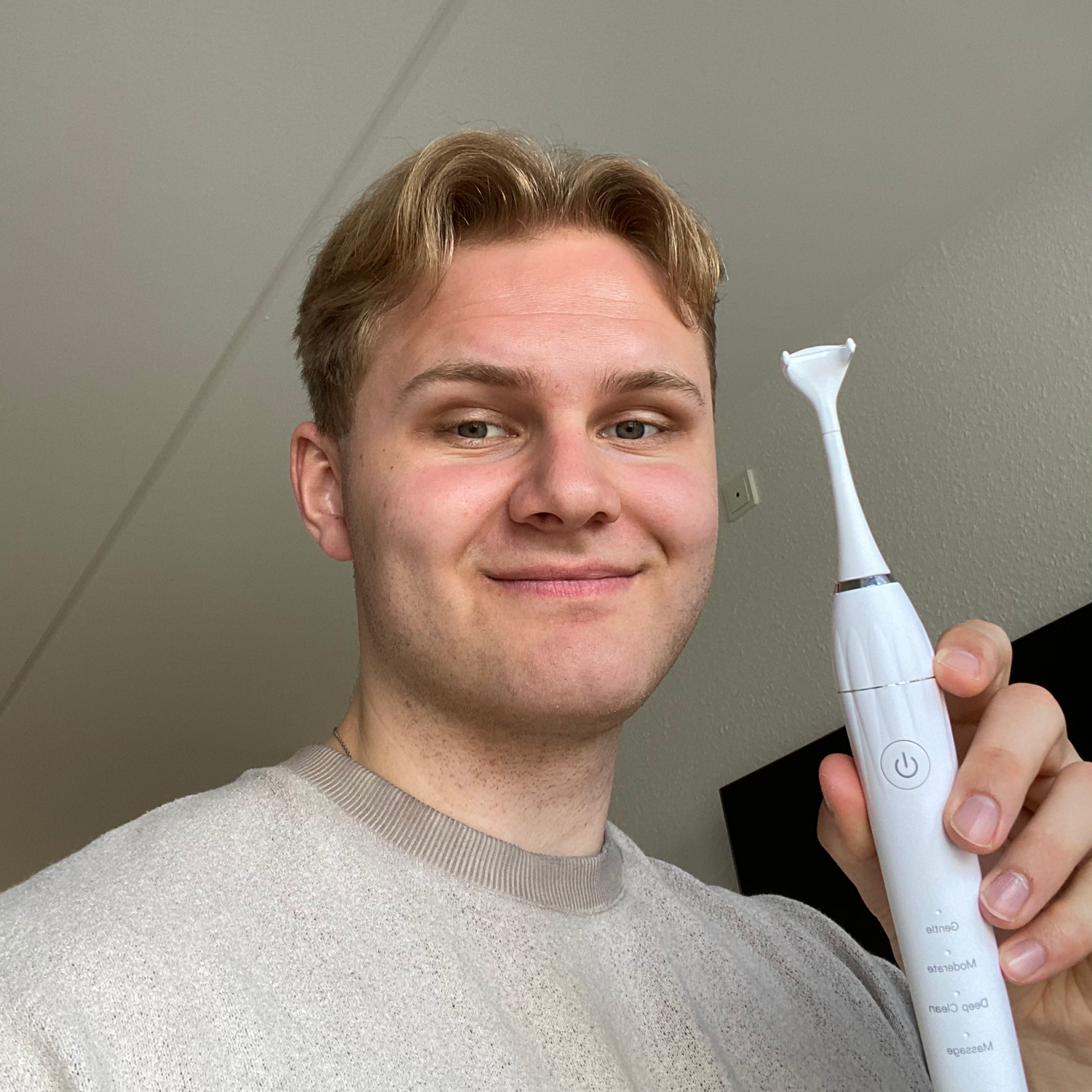 Ejeren af FlossPro står med FlossPro, den elektriske tandtråd i hånden og smiler. Selfie.